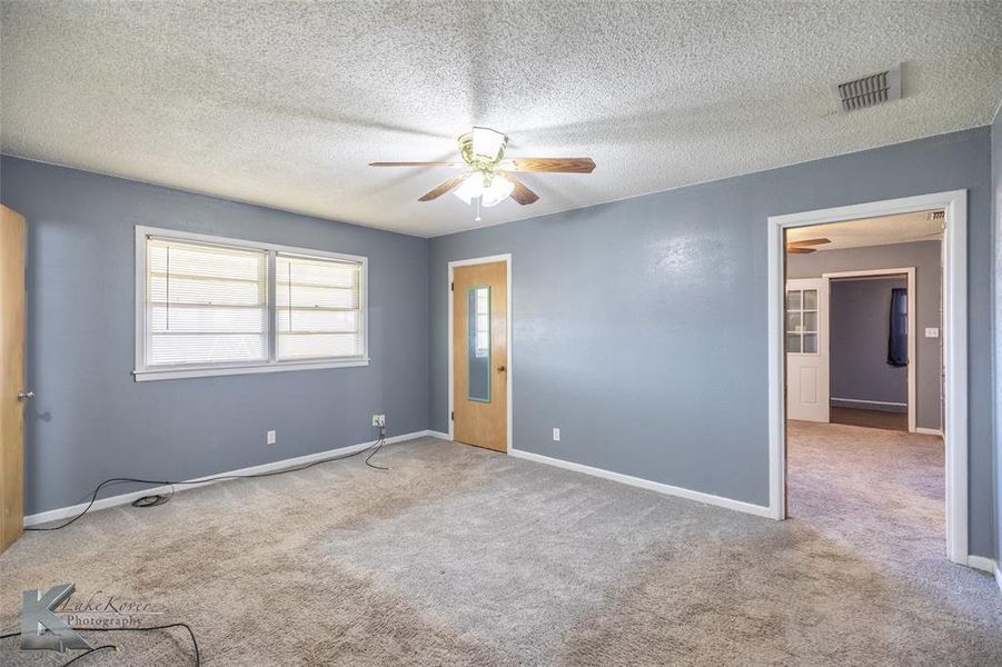 Unfurnished bedroom featuring carpet, a textured ceiling, and a ceiling fan