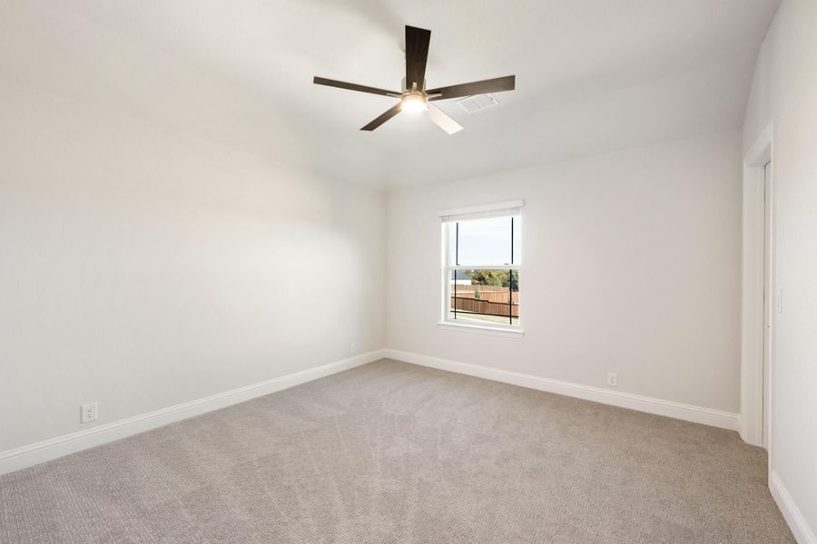 Empty bedroom with gray carpet, ceiling fan, and single window with backyard view Empty bedroom with gray carpet, ceiling fan, and single window with backyard view