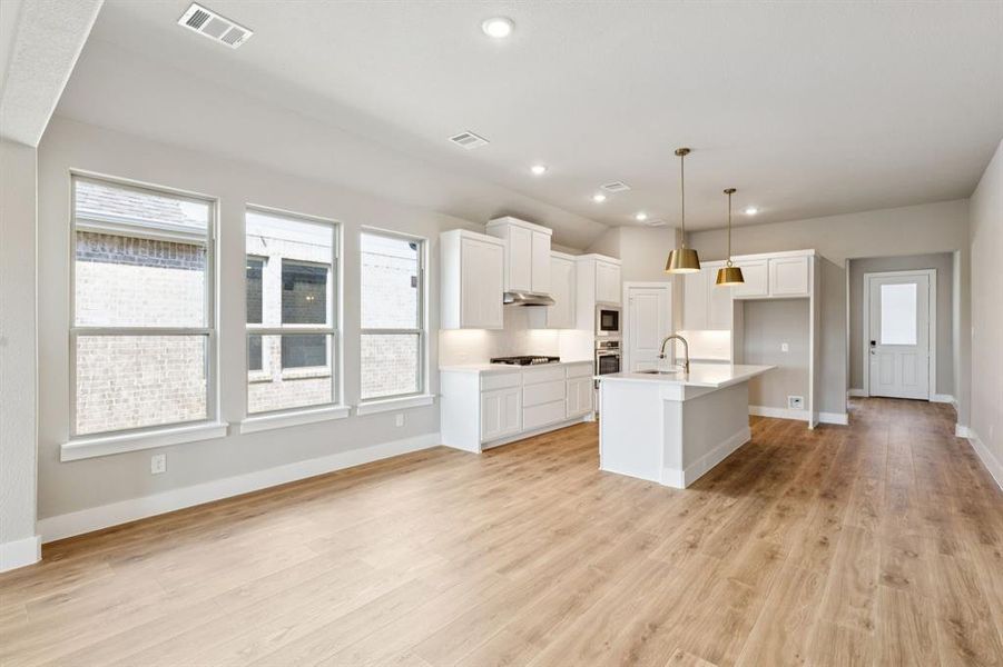 Kitchen featuring recessed lighting, white cabinetry, hanging light fixtures, an island with sink, and a breakfast bar