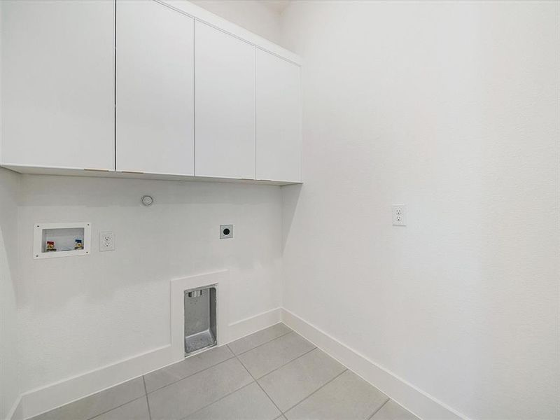 Washroom with light tile patterned floors, electric dryer hookup, cabinet space, washer hookup, and hookup for a gas dryer