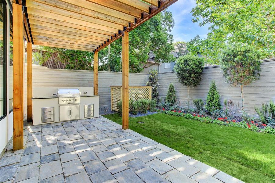 Great outdoor kitchen with pergola and lush landscaping. Please note the 8' cap and rail horizontal cedar fence.