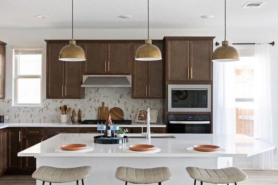 Kitchen with a breakfast bar, dark wood finish cabinetry, and a center island with sink Kitchen with a breakfast bar, dark wood finish cabinetry, and a center island with sink