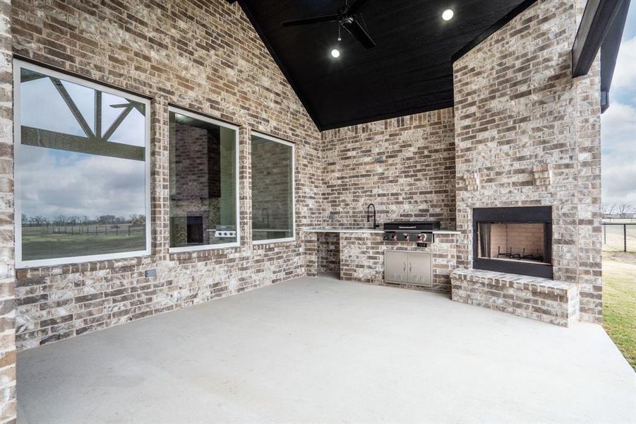 View of patio featuring area for grilling, an outdoor brick fireplace, grilling area, and ceiling fan