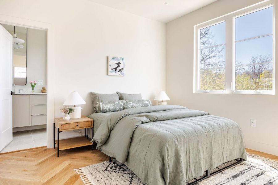 Primary bedroom with ensuite bathroom and herringbone flooring.