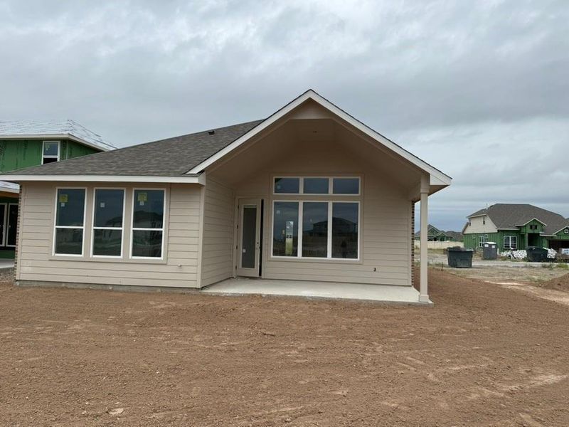 Back of house featuring a patio area and roof with shingles
