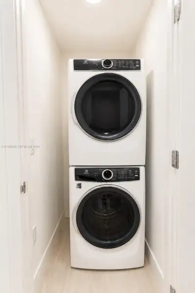 Laundry closet featuring a white, stackable front-loading washer and dryer set