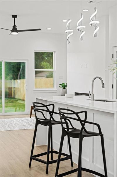 Kitchen featuring pendant lighting, light wood-style floors, light stone counters, recessed lighting, and a ceiling fan