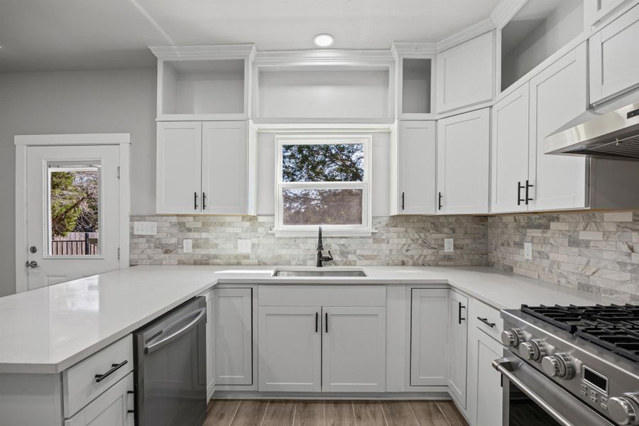 Kitchen with white cabinetry, appliances with stainless steel finishes, open shelves, a peninsula, and healthy amount of natural light Kitchen with white cabinetry, appliances with stainless steel finishes, open shelves, a peninsula, and healthy amount of natural light