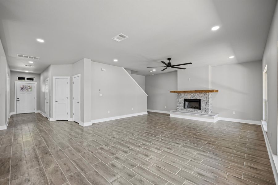 Unfurnished living room featuring recessed lighting, wood tiled floors, a fireplace with raised hearth, and ceiling fan Unfurnished living room featuring recessed lighting, wood tiled floors, a fireplace with raised hearth, and ceiling fan