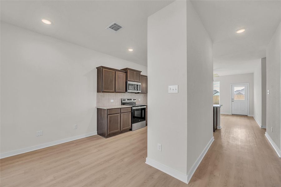 Kitchen featuring stainless steel appliances, dark brown cabinets, decorative backsplash, recessed lighting, and light wood-style flooring
