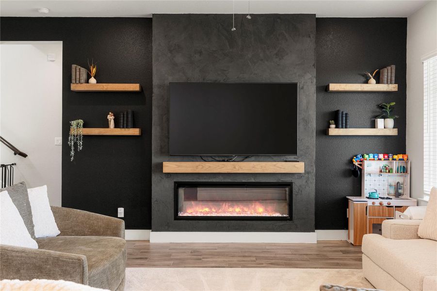 A stylish living room features an inviting fireplace, complemented by floating shelves and wood-look flooring. A stylish living room features an inviting fireplace, complemented by floating shelves and wood-look flooring.