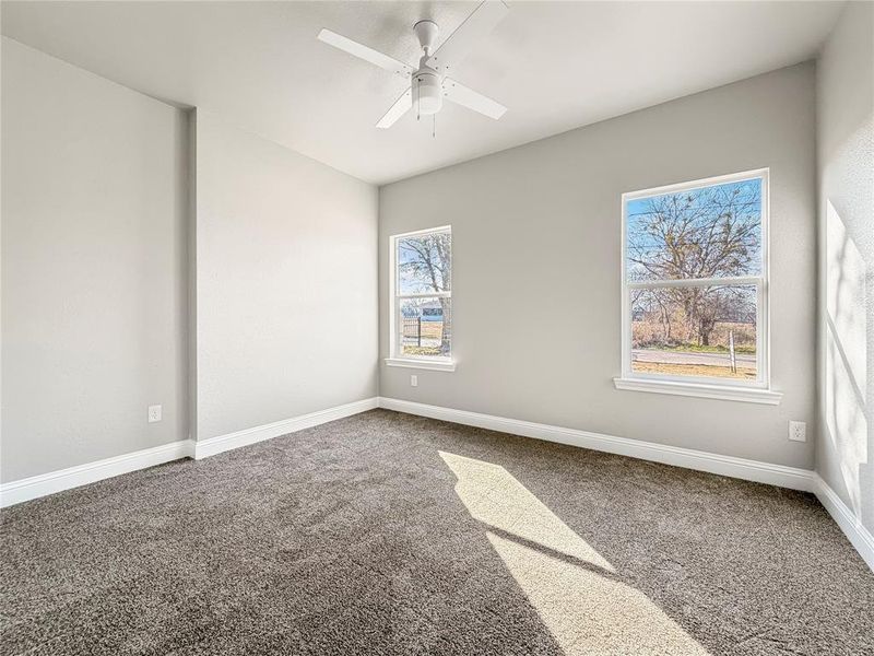 Carpeted empty room with baseboards and ceiling fan Carpeted empty room with baseboards and ceiling fan