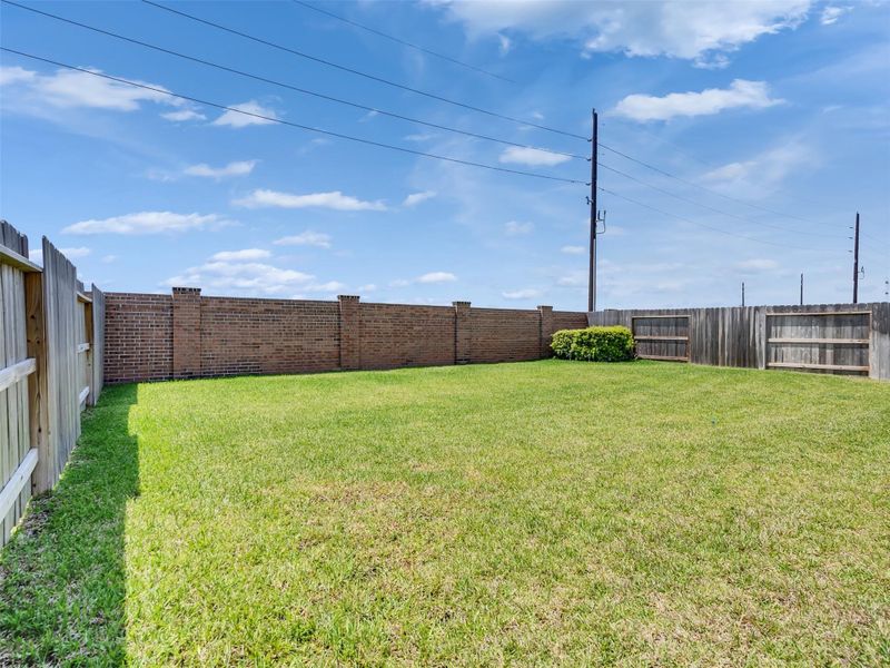 Spacious fenced backyard with lush green lawn, perfect for outdoor activities and privacy.