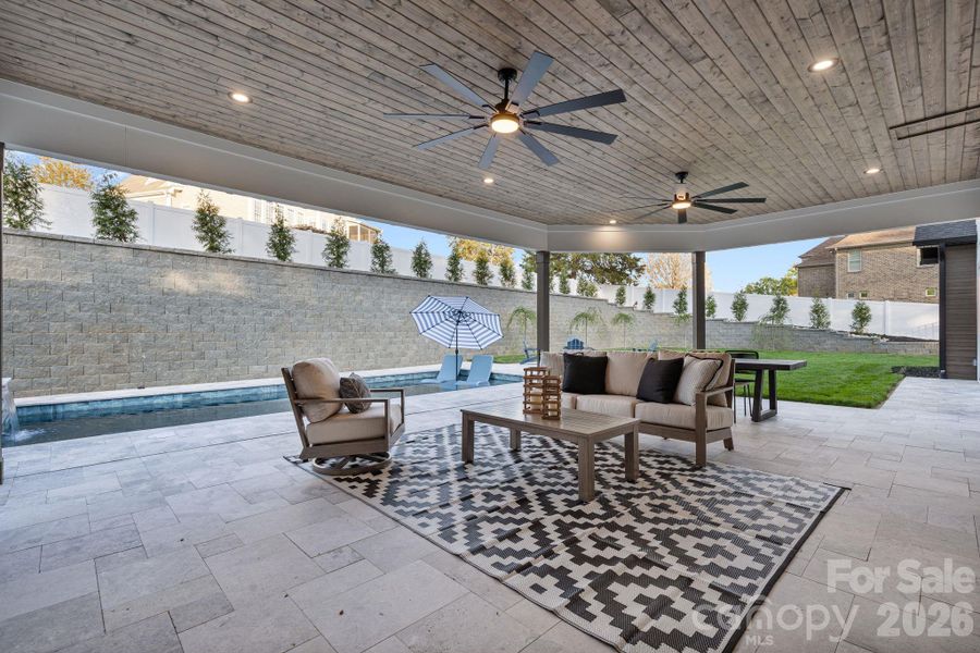 Covered Travertine back patio and privacy fence surrounding the backyard