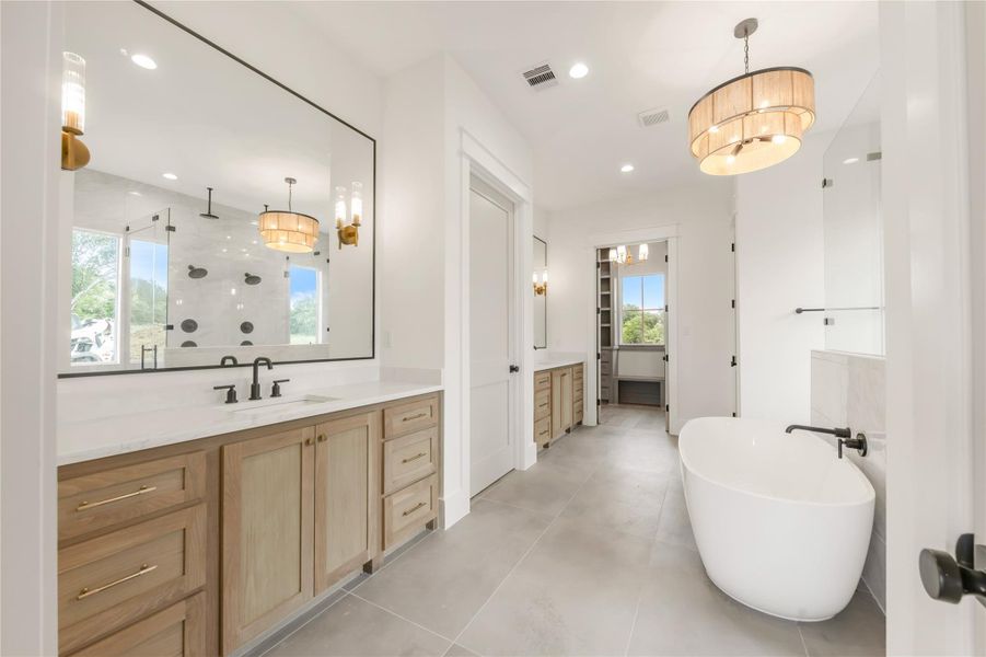 Bathroom featuring vanity, hanging lights, a freestanding tub, and a stall shower