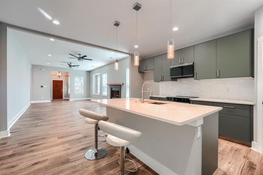 Kitchen with decorative light fixtures, light stone counters, decorative backsplash, and sink