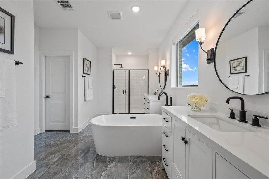 Primary 
bathroom with vanity, a stall shower, a freestanding bath, dark marble finish floors, and recessed lighting
