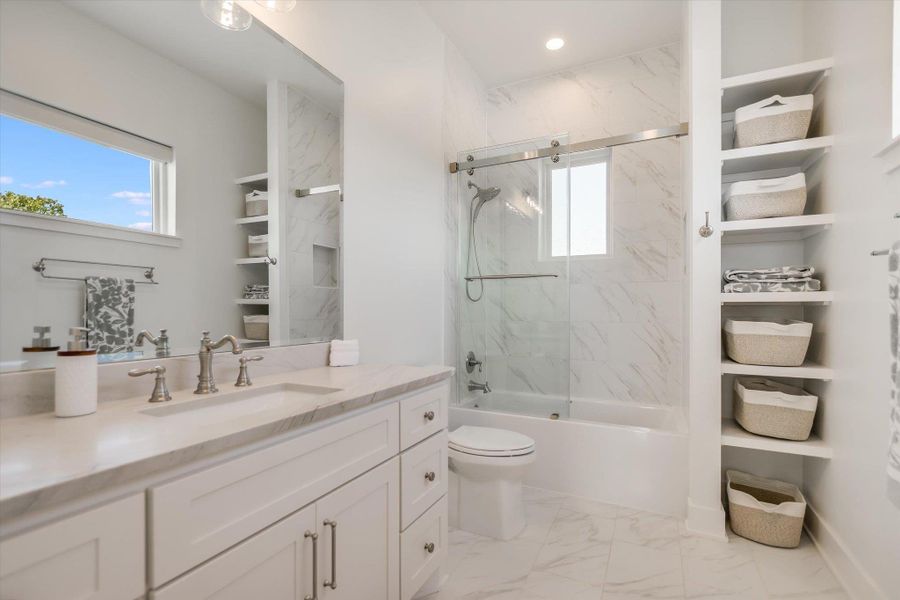 Bathroom featuring marble finish floors, healthy amount of natural light, vanity, toilet, and recessed lighting Bathroom featuring marble finish floors, healthy amount of natural light, vanity, toilet, and recessed lighting