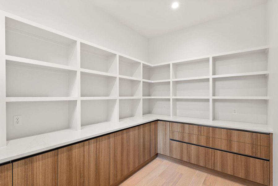 Floor-to-ceiling custom shelving and warm wood cabinetry wrap around this functional walk-in pantry.