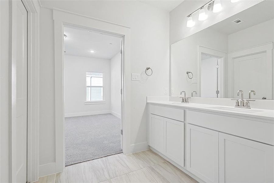 The bathroom features a dual vanity with white cabinetry, light-colored countertops, and chrome fixtures