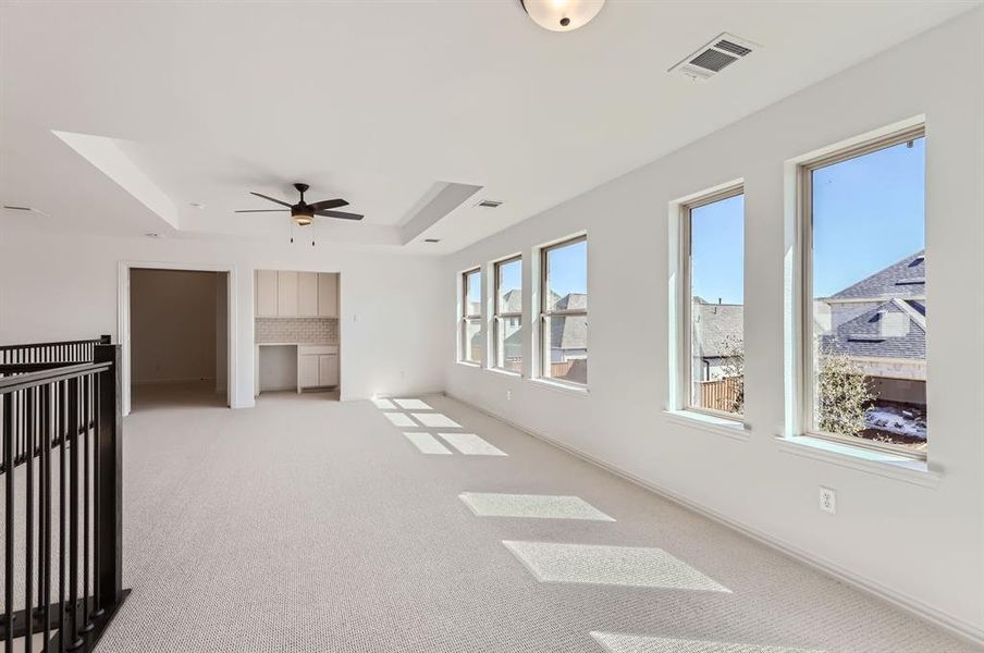 Unfurnished room featuring light carpet, a tray ceiling, and ceiling fan