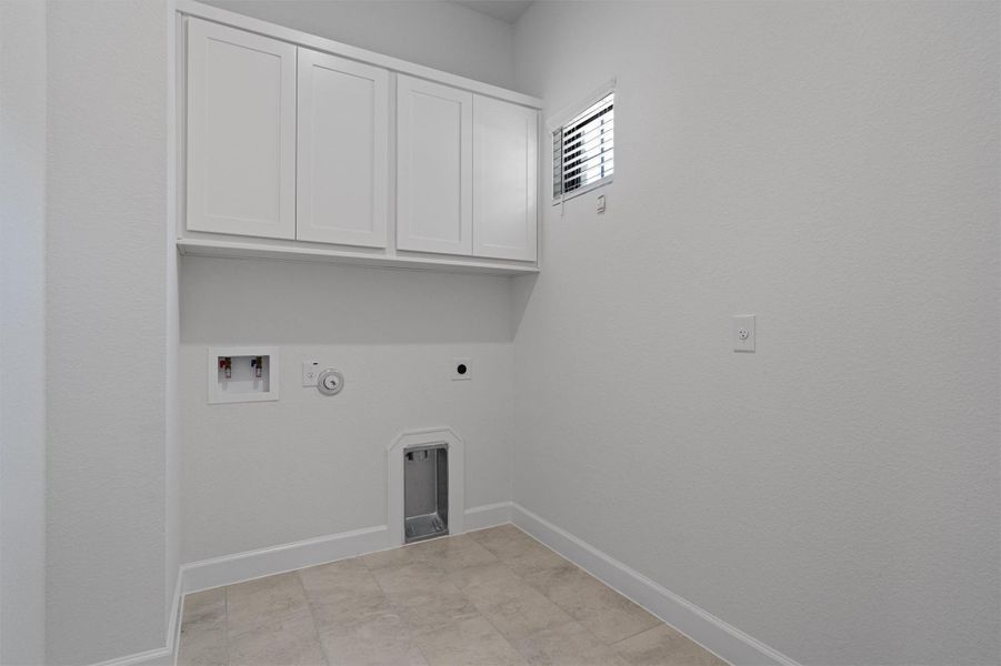 Laundry area featuring white cabinetry, tile flooring, and essential utility hookups