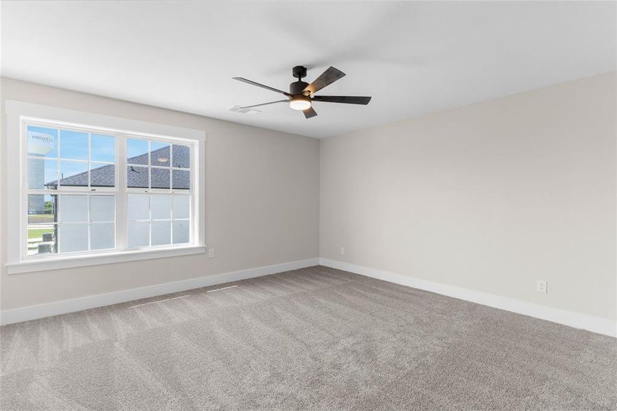 Spacious room featuring neutral carpeting, light-toned walls, and a modern ceiling fan with integrated lighting