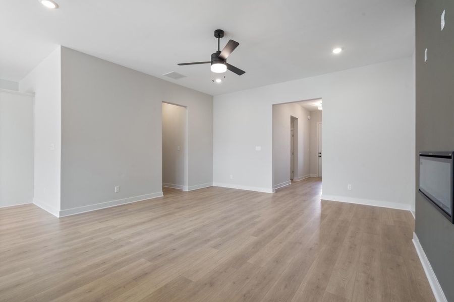 Recessed ceiling lighting, wood-finish flooring, a ceiling fan with light, and an integrated wall-mounted electric fireplace Recessed ceiling lighting, wood-finish flooring, a ceiling fan with light, and an integrated wall-mounted electric fireplace