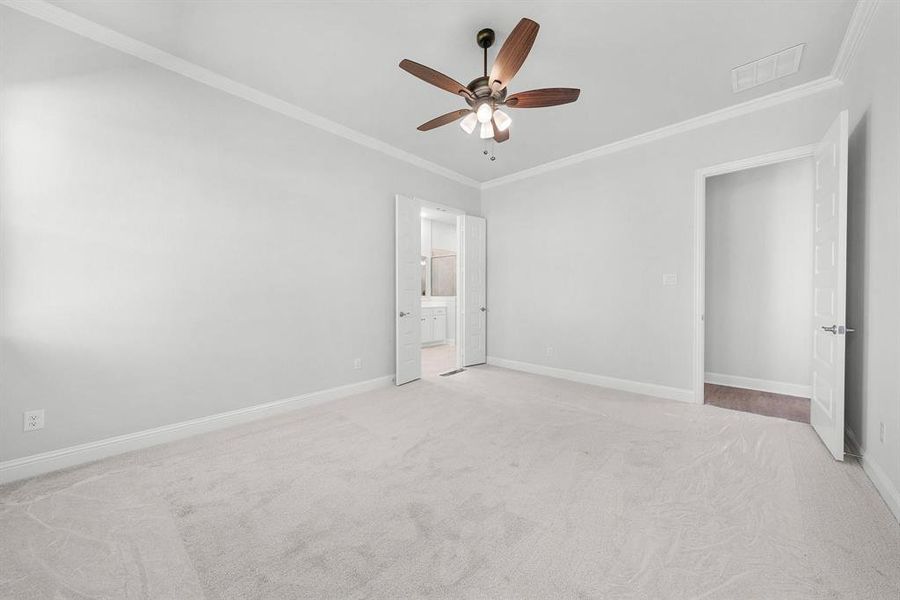 Primary bedroom featuring crown molding, carpet flooring, ensuite bathroom, and ceiling fan