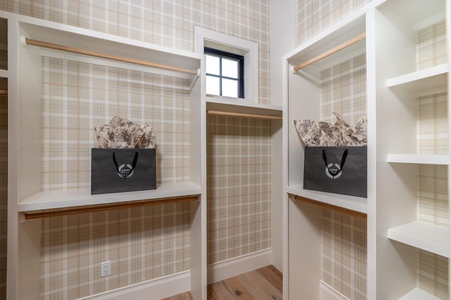 His Master Closet with wallpapered walls and light wood-type flooring