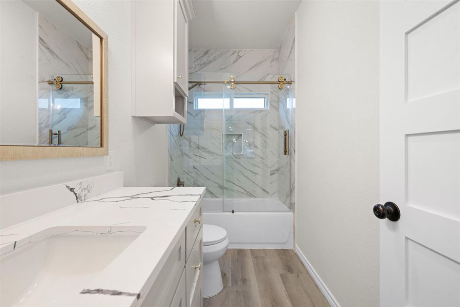 A well-appointed bathroom features a sleek vanity, elegant marble-patterned tile, and durable wood-look flooring. A well-appointed bathroom features a sleek vanity, elegant marble-patterned tile, and durable wood-look flooring.