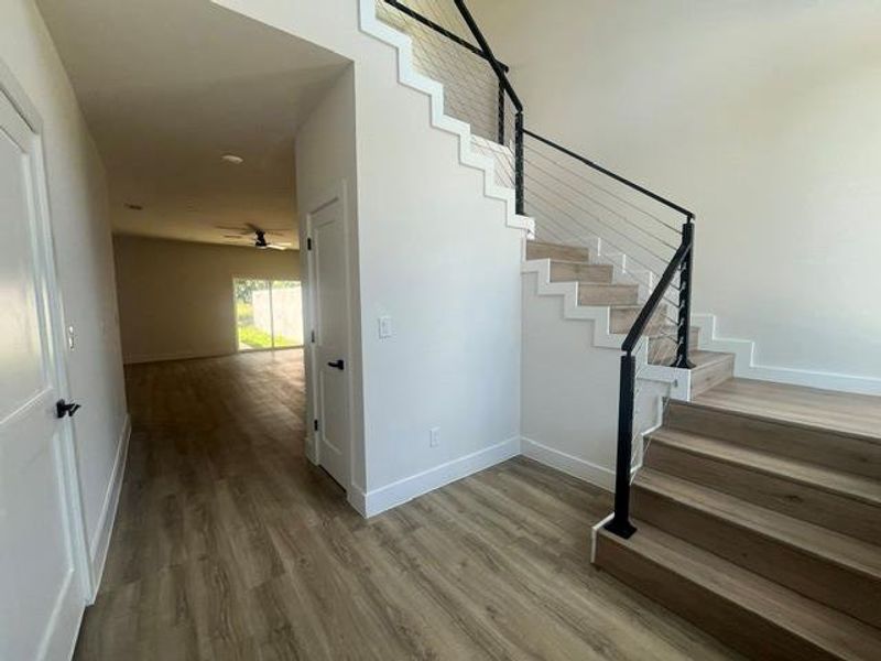 Modern staircase featuring a black metal handrail with cable infill, wood-finish treads, and crisp white risers Modern staircase featuring a black metal handrail with cable infill, wood-finish treads, and crisp white risers