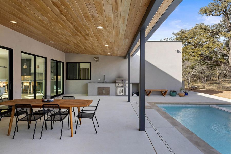 View of patio with exterior kitchen, outdoor dining space, and an outdoor pool