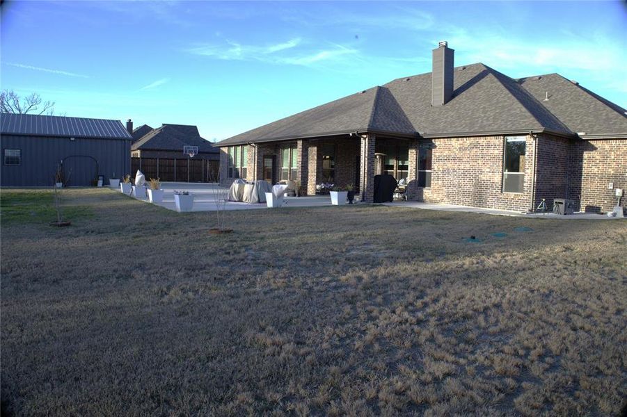 New Addition - Back of house featuring brick siding, a patio area, a chimney, and a shingled roof