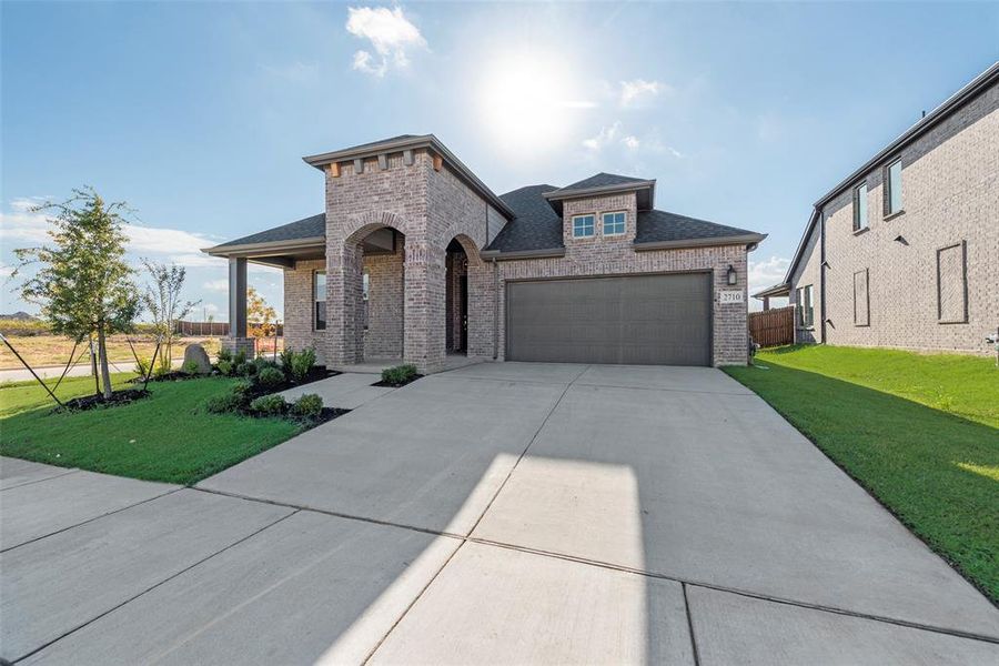 French provincial home with brick siding, driveway, a shingled roof, and a garage