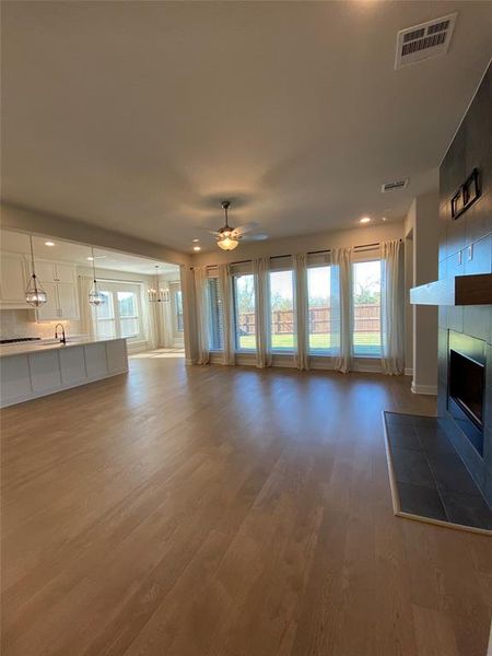 Unfurnished living room featuring ceiling fan, a tile fireplace, recessed lighting, light wood-style floors, and a chandelier Unfurnished living room featuring ceiling fan, a tile fireplace, recessed lighting, light wood-style floors, and a chandelier
