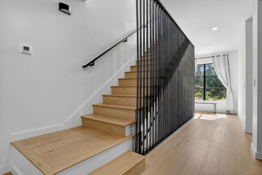 Stairway with wood finished floors and recessed lighting