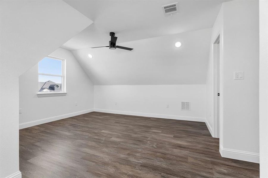 Bonus room with dark wood-type flooring, ceiling fan, and vaulted ceiling