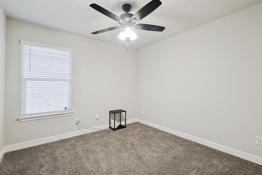 Carpeted spare room with baseboards and a ceiling fan