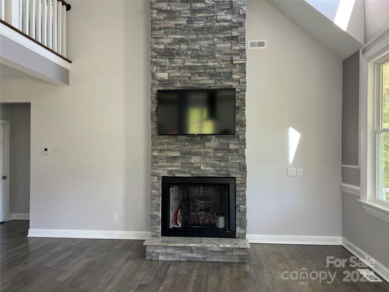 TV screen over stone fireplace with gas logs