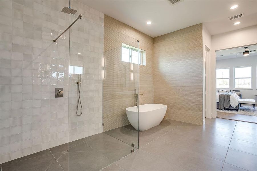 Full bath featuring walk in shower, ensuite bathroom, tile patterned flooring, a freestanding tub, and tile walls Full bath featuring walk in shower, ensuite bathroom, tile patterned flooring, a freestanding tub, and tile walls