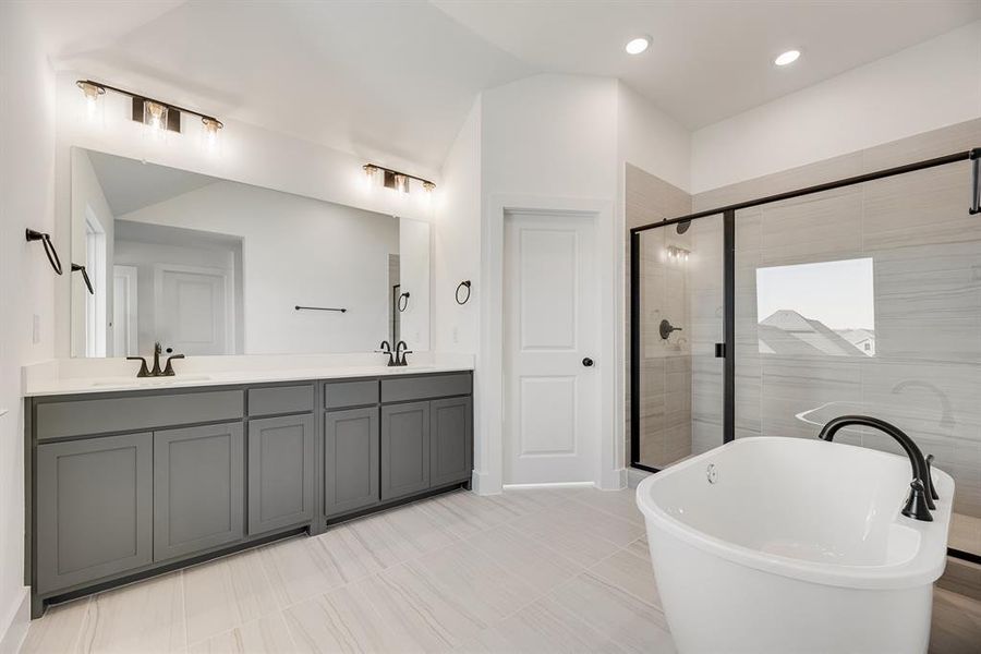 Bathroom featuring double vanity, a freestanding bath, a shower stall, recessed lighting, and vaulted ceiling