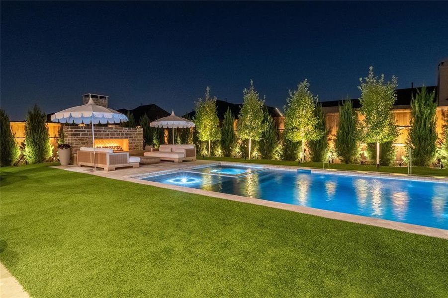 Pool at twilight featuring a fire pit, a patio, an in ground hot tub, and a lawn