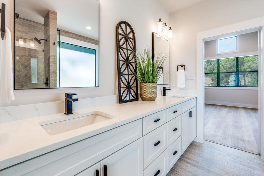 Bathroom with double vanity, healthy amount of natural light, and a shower stall