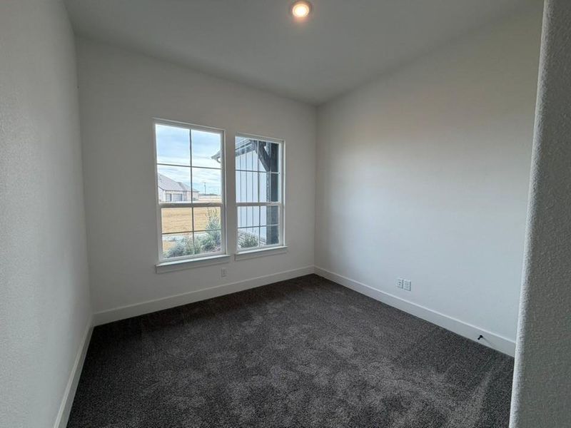 Spare room with dark carpet and baseboards