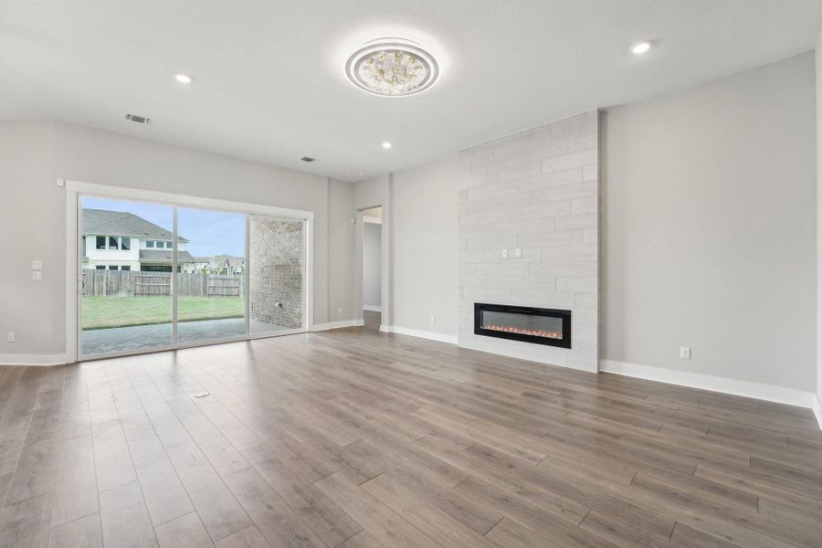 Unfurnished living room featuring visible vents, baseboards, recessed lighting, wood finished floors, and a fireplace Unfurnished living room featuring visible vents, baseboards, recessed lighting, wood finished floors, and a fireplace