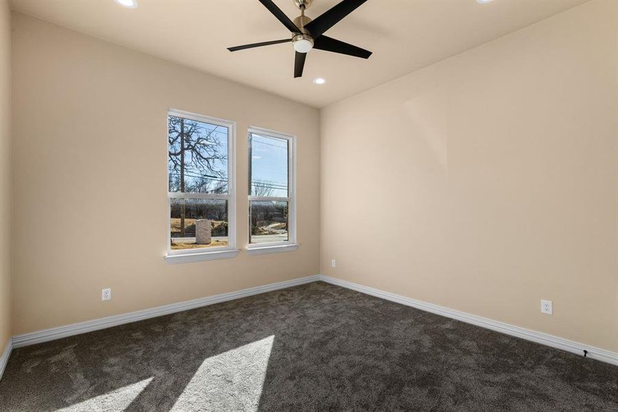 Empty room featuring ceiling fan and dark carpet