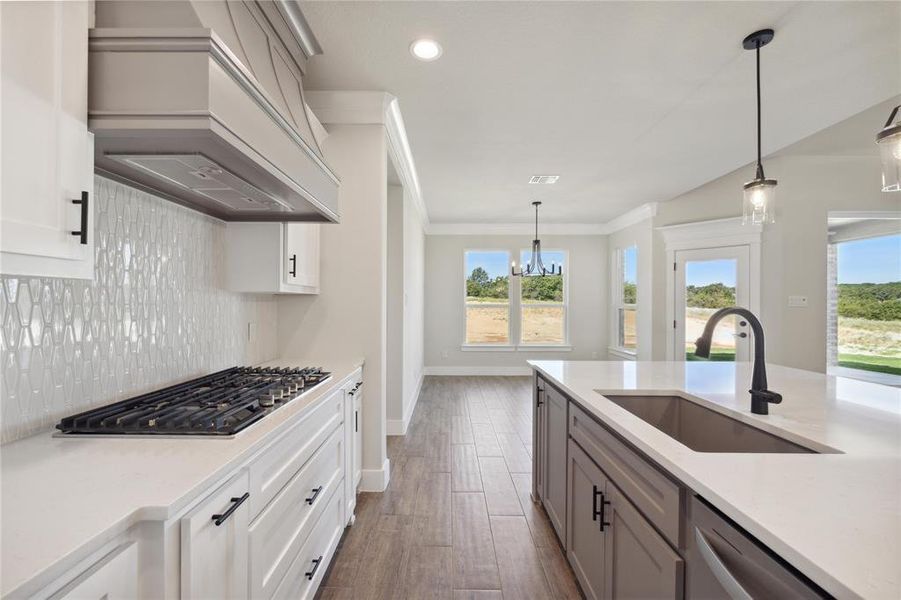 Kitchen featuring sink, hanging light fixtures, custom exhaust hood, stainless steel appliances, and dark hardwood / wood-style flooring