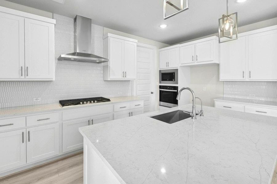 Kitchen with wall chimney range hood, light stone counters, white cabinetry, appliances with stainless steel finishes, and pendant lighting