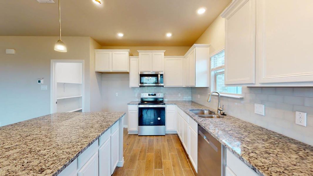 Kitchen featuring appliances with stainless steel finishes, hanging light fixtures, white cabinets, wood finish floors, and recessed lighting Kitchen featuring appliances with stainless steel finishes, hanging light fixtures, white cabinets, wood finish floors, and recessed lighting